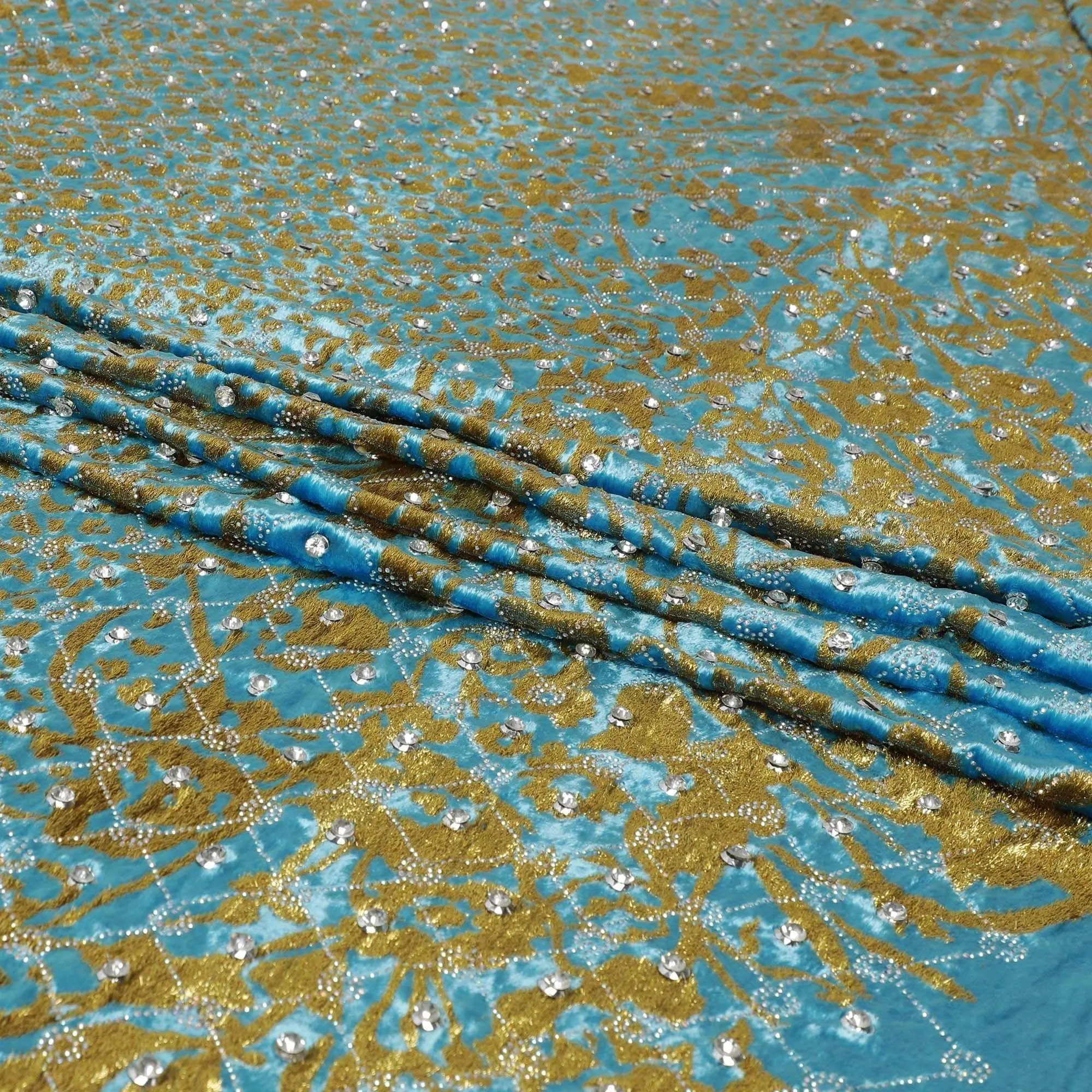 cerulean blue Rayon velvet fabric with metallic gold fringe embroidery and white stones in abstract design